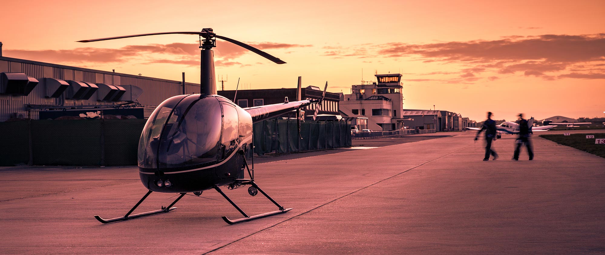 Robinson R22 helicopter with Shoreham Airport 1930s terminal in background